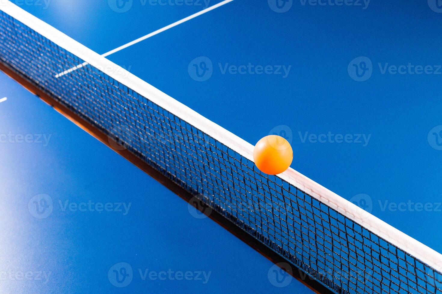 Table tennis ball near the net on blue table photo
