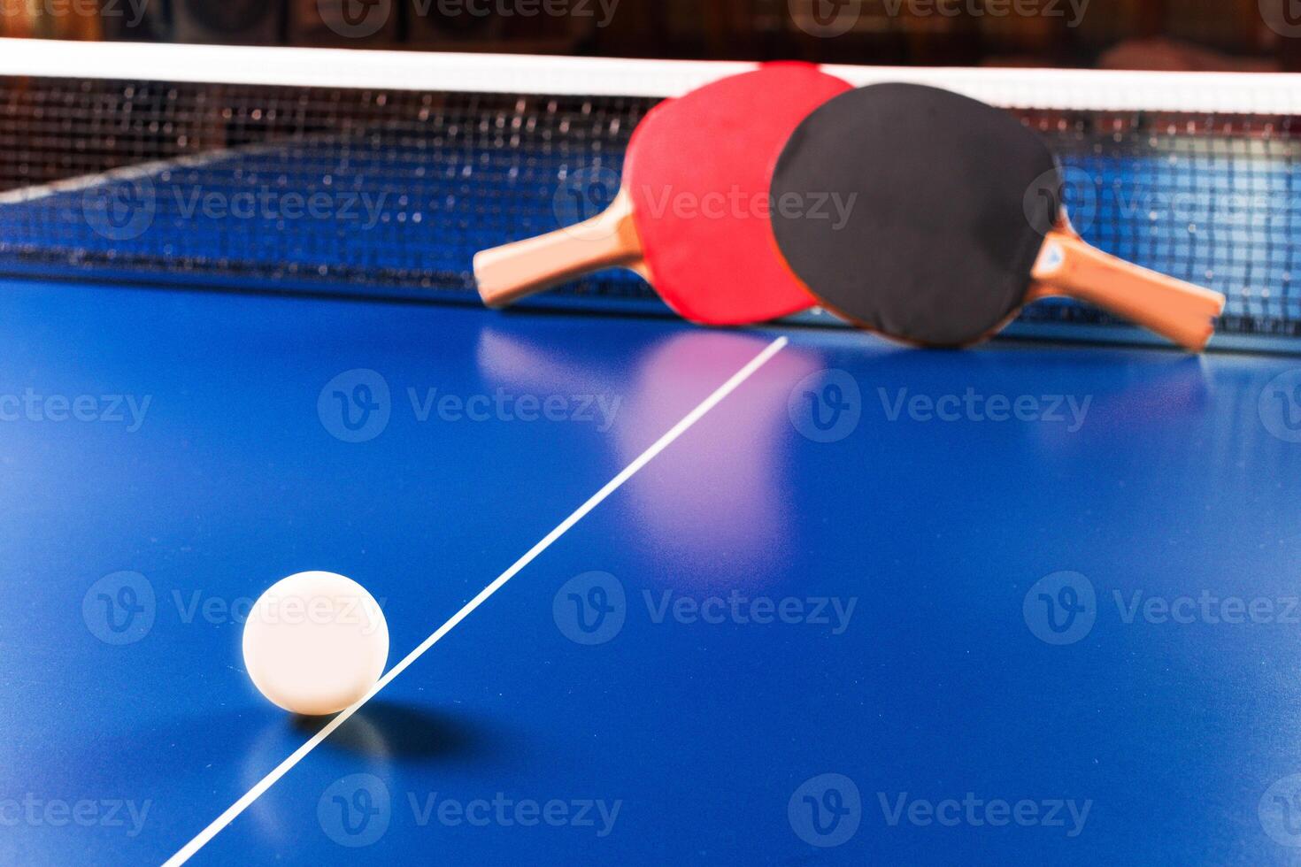 Two ping pong rackets and ball on blue table photo
