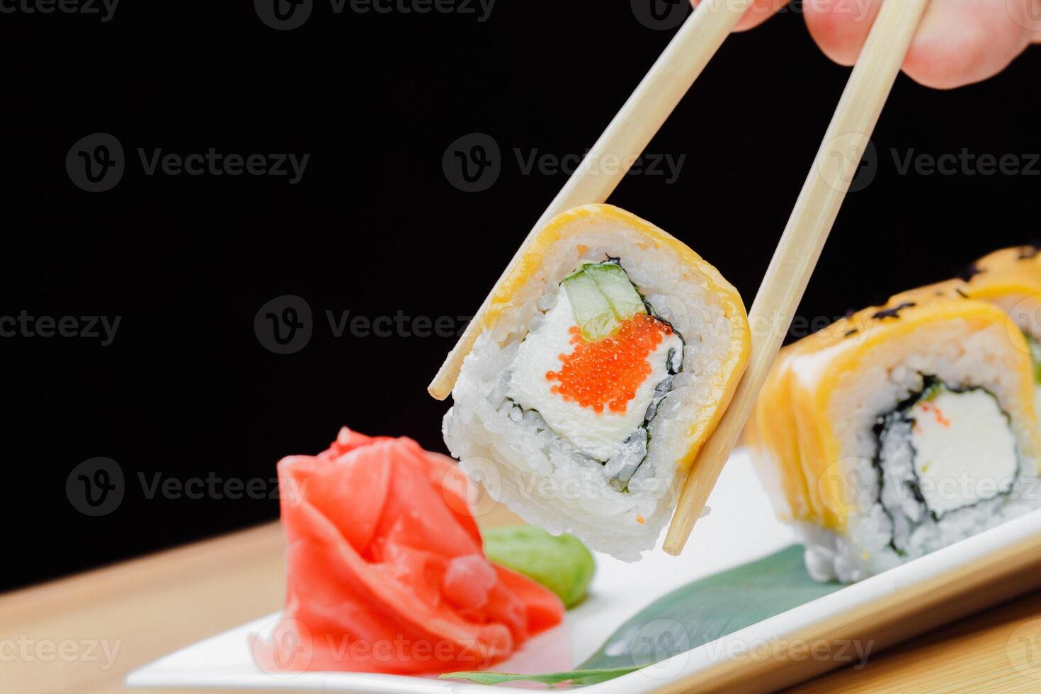 Delicious sushi roll being picked up with chopsticks in a restaurant setting photo