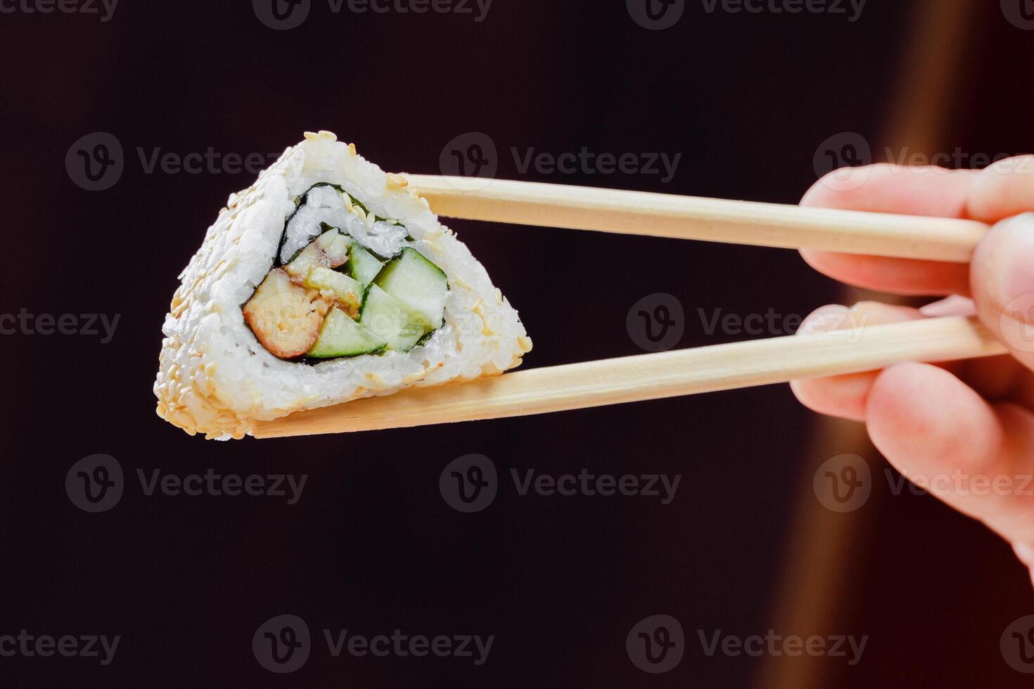 Sushi roll held with chopsticks showcases fresh ingredients and meticulous preparation in a modern setting photo