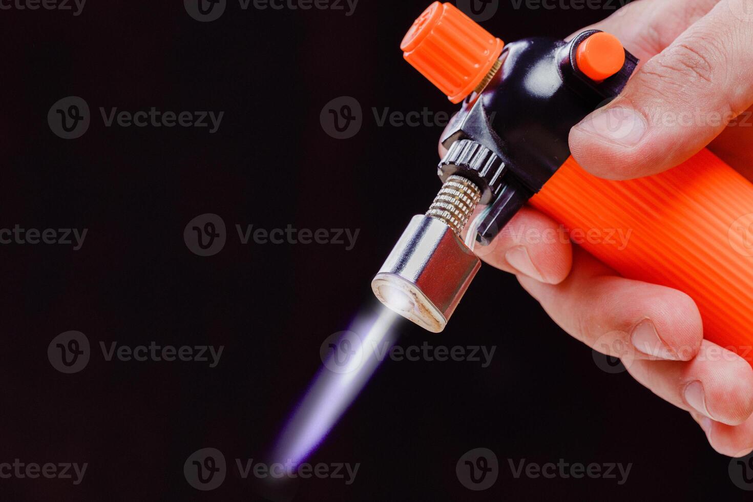 Men's hand holding gas can with manual torch burner for cooking photo