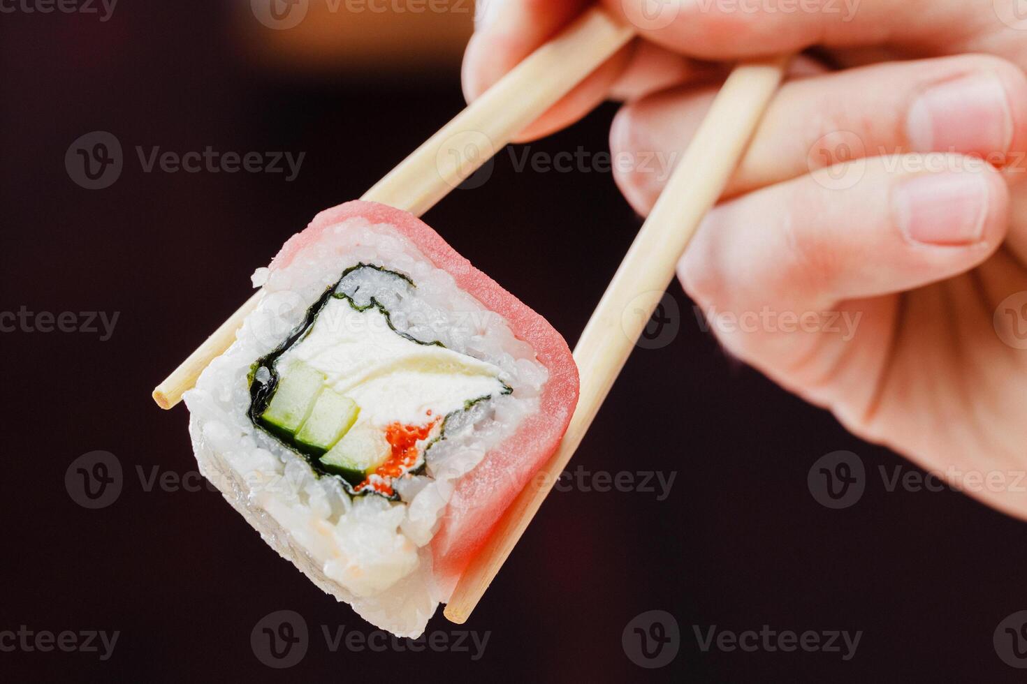 Delicious sushi roll held up with chopsticks showcasing vibrant ingredients and expert craftsmanship photo