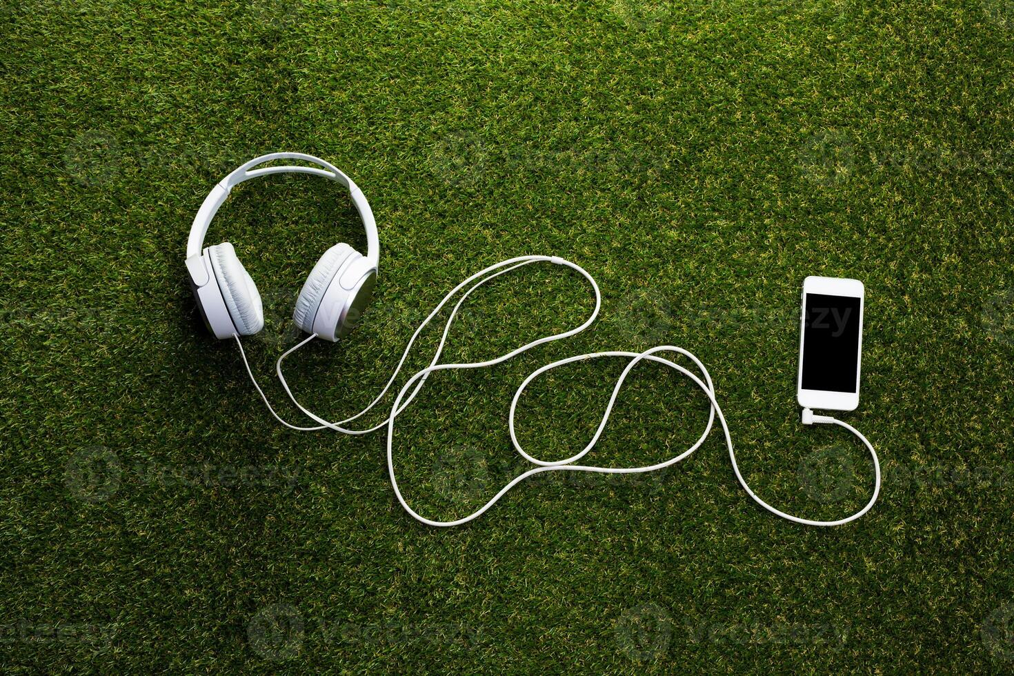 White headphones with cord on grass top view photo