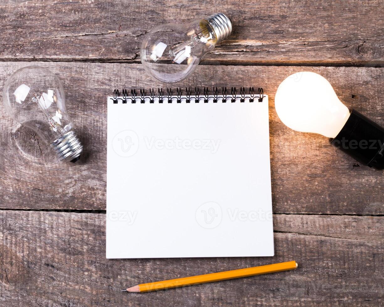 Lightbulb and blank open notepad. Having an idea concept photo