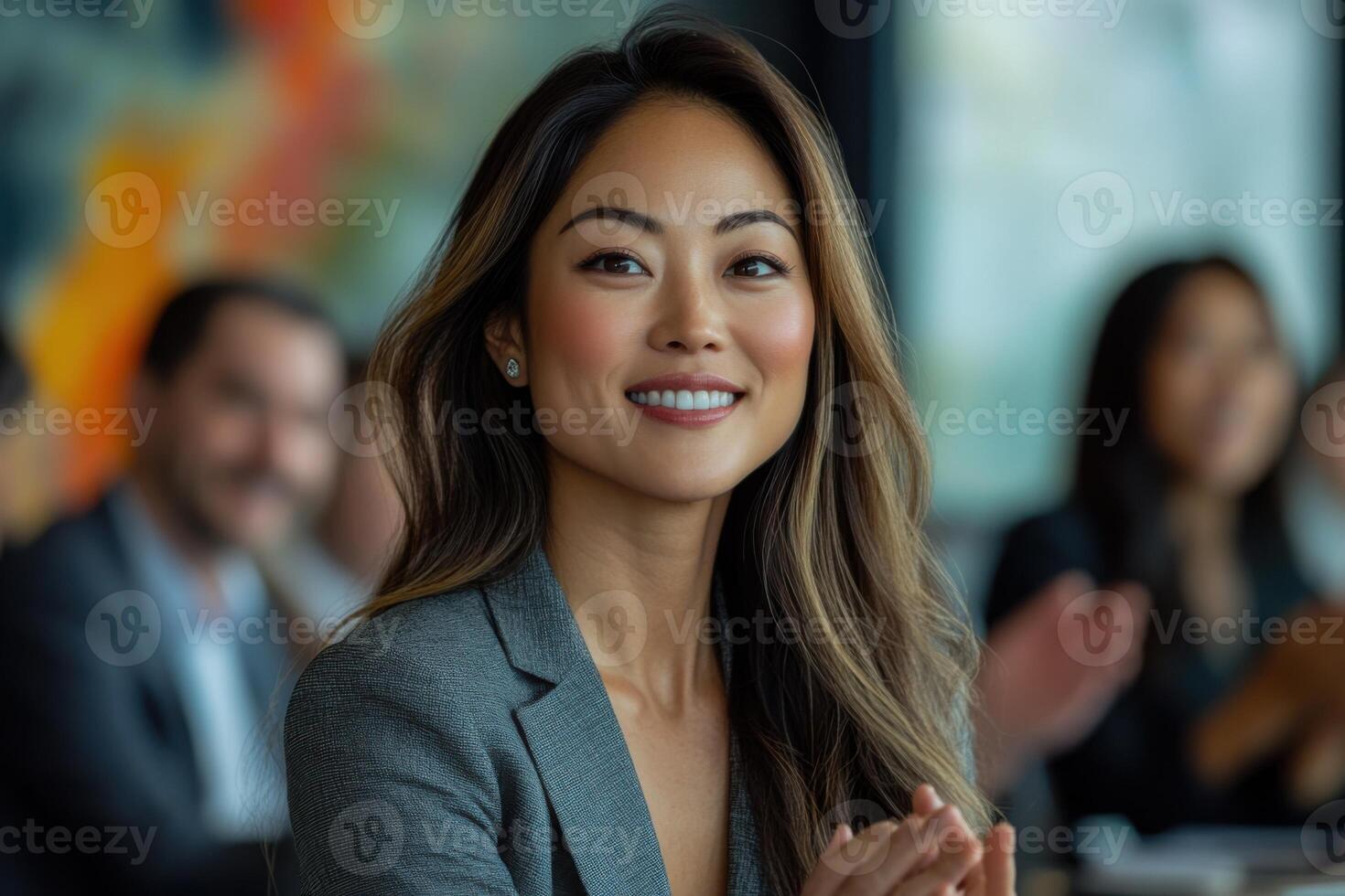 Smiling woman in jacket, applause. Group of people in background. Business meeting or conference scene. Office environment. Happy and positive expression. photo