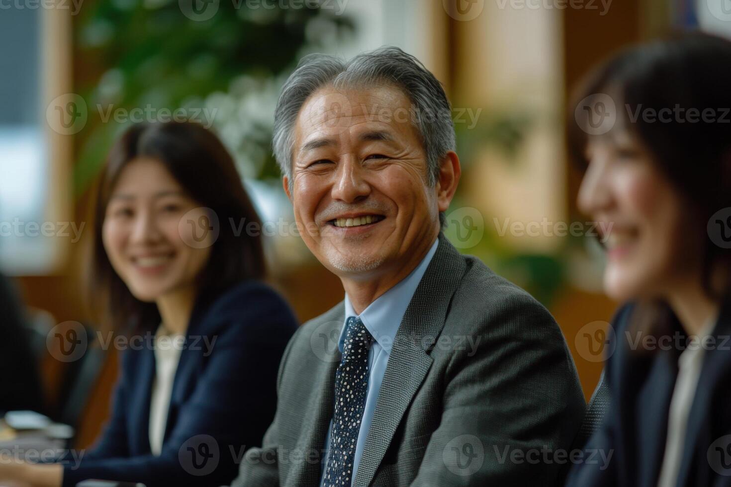 Smiling people at meeting. Man in suit. Business colleagues smiling. Happy faces in office. Group is in discussion. Teamwork is key. photo