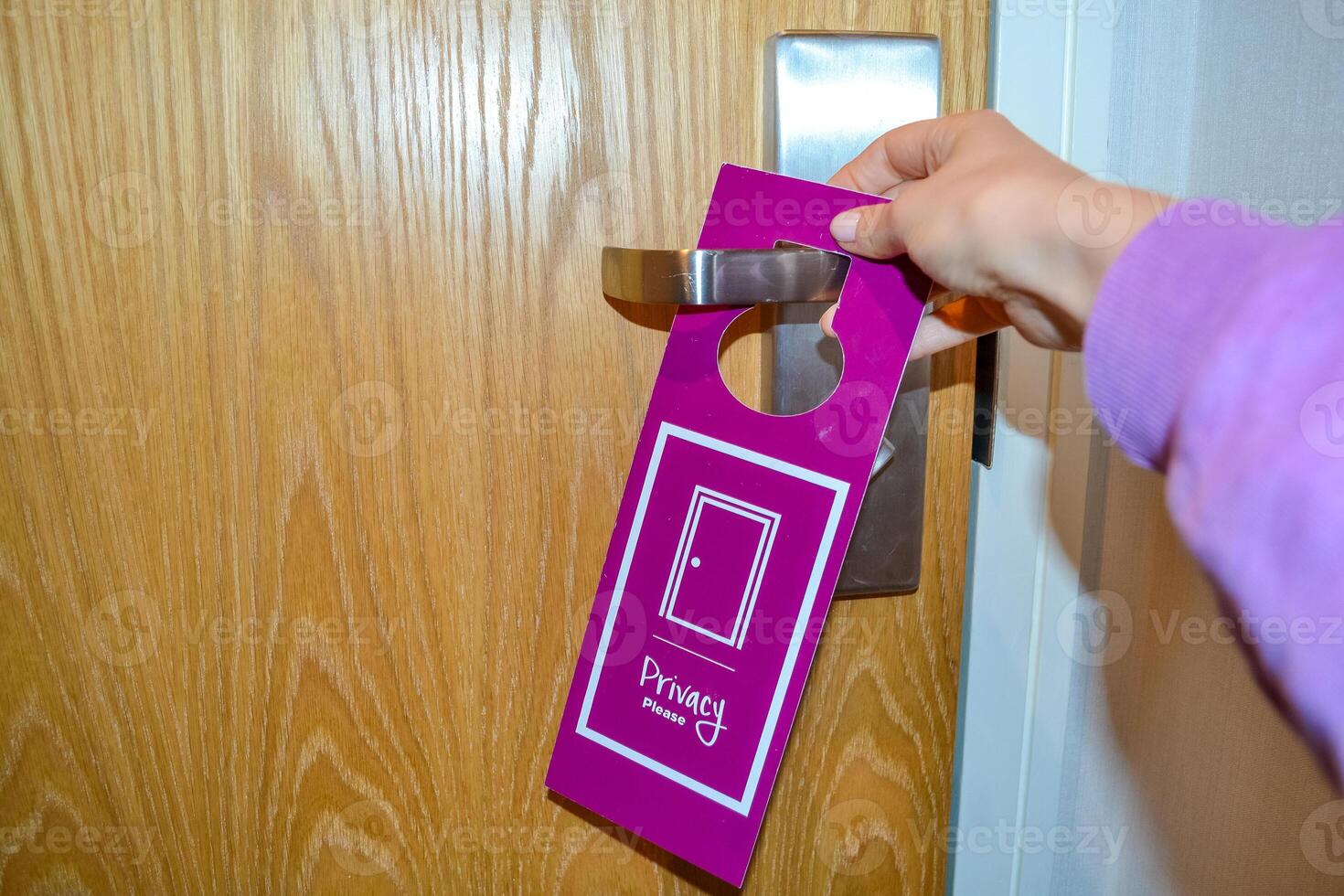 Woman's hand hangs a do not disturb sign to request privacy photo