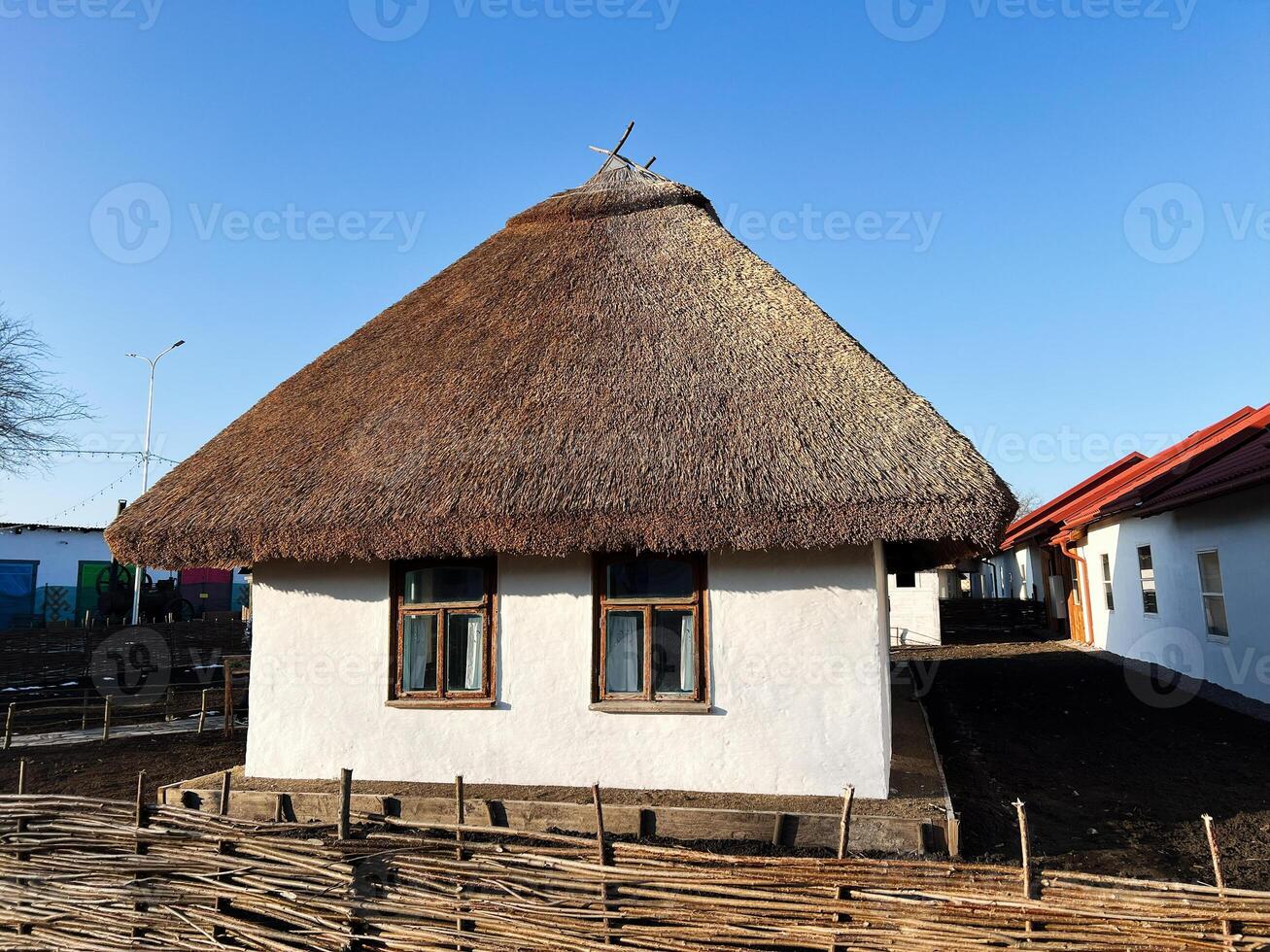 Traditional rural house with a thatched roof and woven fence photo