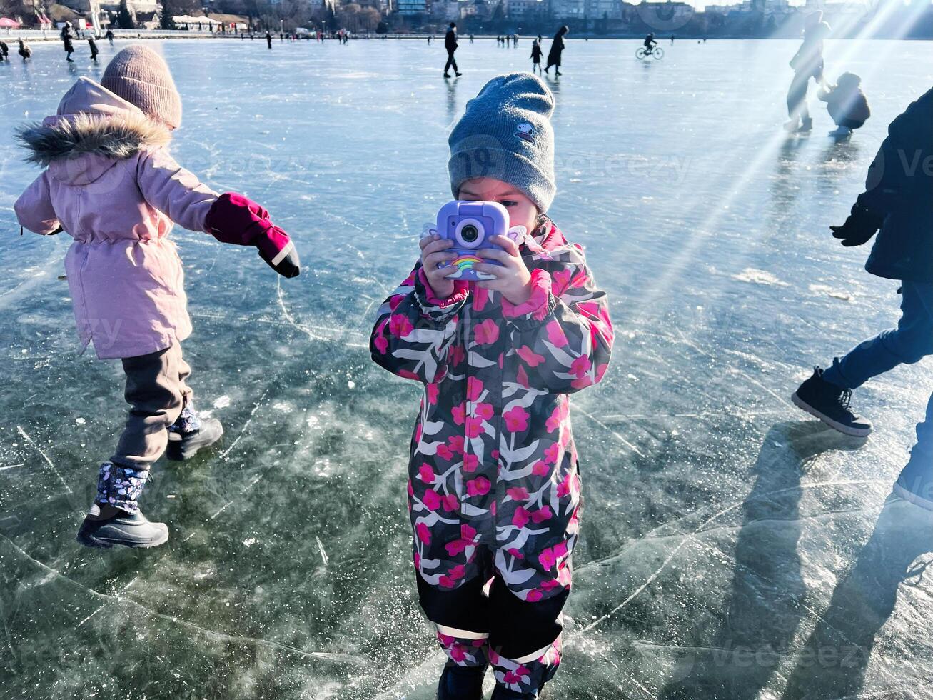Child photographing while ice skating on a sunny winter day outdoors photo