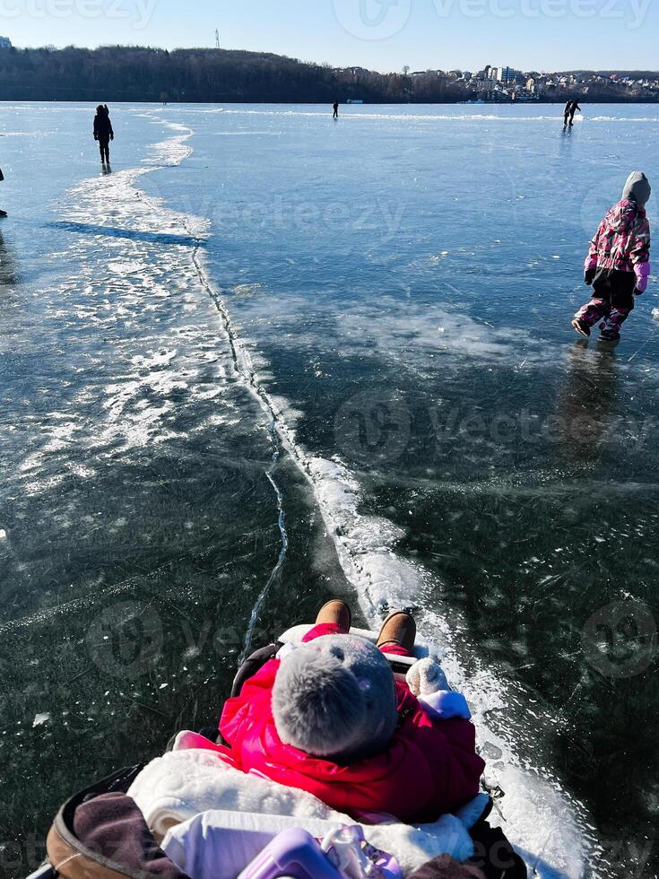 Family enjoying a sunny winter day on a frozen ice-covered lake photo