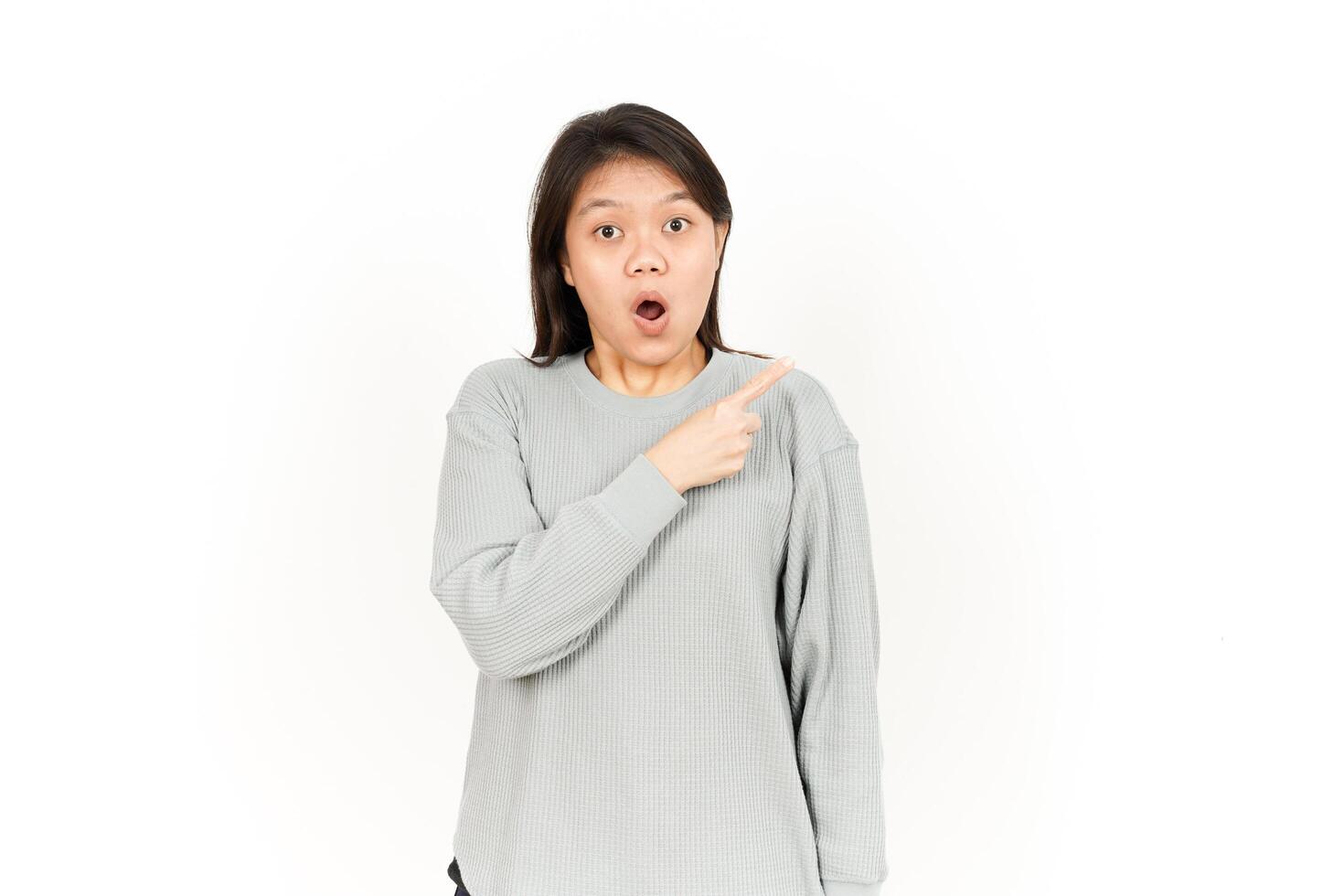 A woman in a grey sweatshirt pointing to her mouth photo