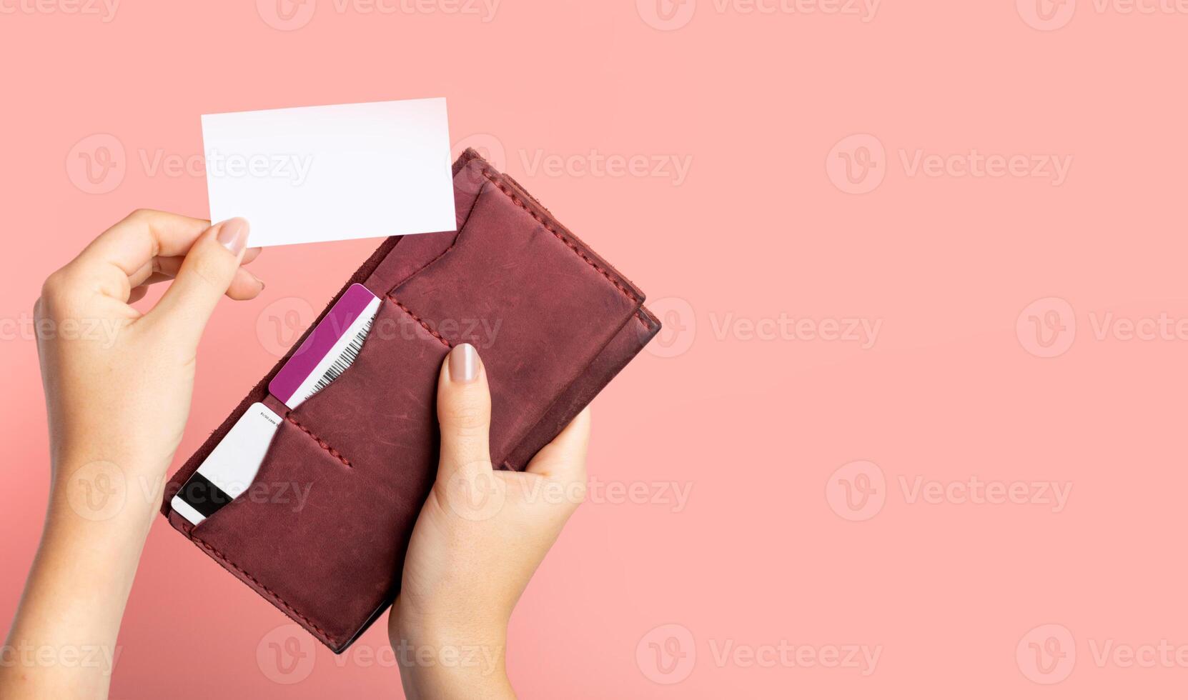 Female hand holds a burgundy leather purse with credit cards and takes out a blank business card photo