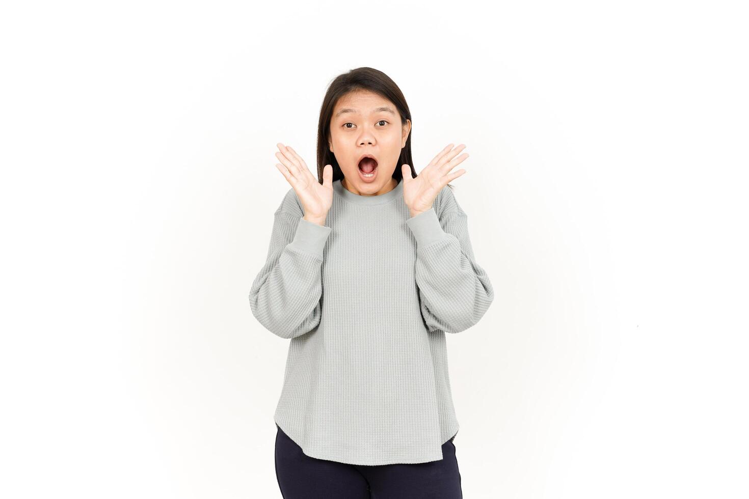 A woman is making a surprised face while standing in front of a white background photo