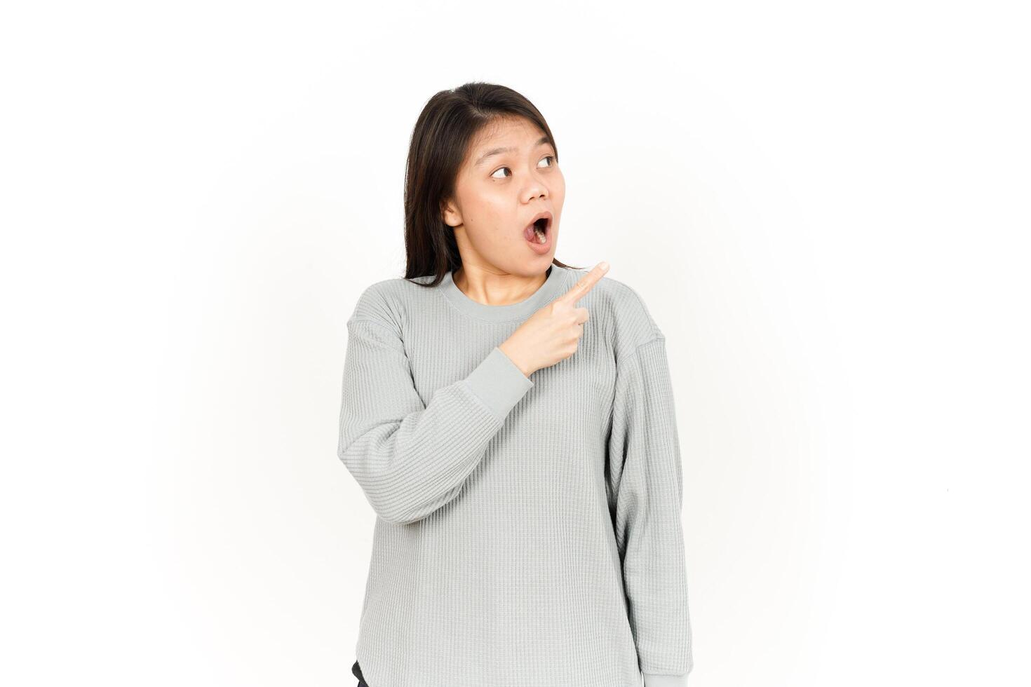 A woman is pointing to her mouth while wearing a grey sweatshirt photo