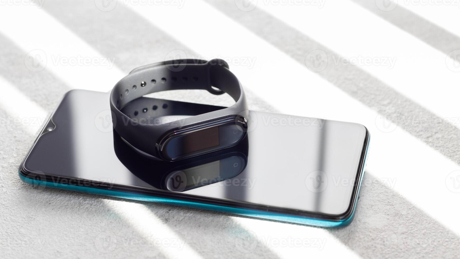 Black fitness watch activity tracker. Fitness tracker lies on a smartphone on a light background photo