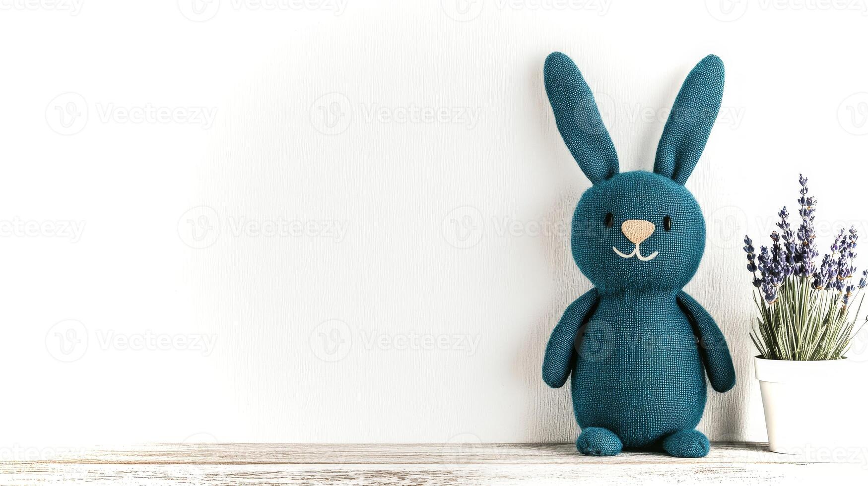 A handcrafted teal rabbit toy is placed on a light wooden surface, accompanied by a small pot of lavender flowers. The setting is cozy and inviting. photo