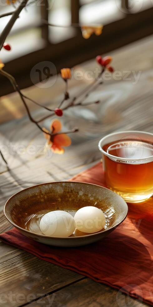 A bowl of cuisine and a cup of amber liquid on a wooden table photo