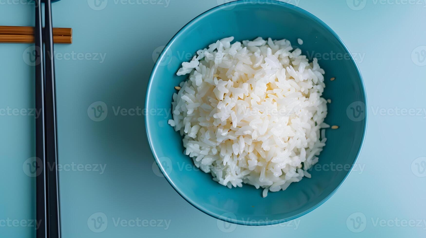 Top View of White Rice in Blue Bowl with Chopsticks on Side photo