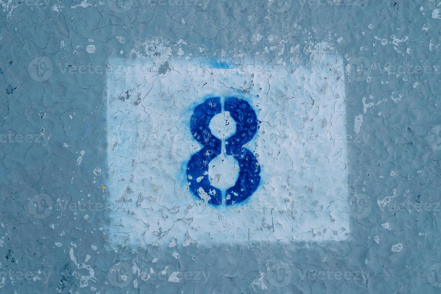 Number eight painted on a peeling blue wall in a rectangle photo