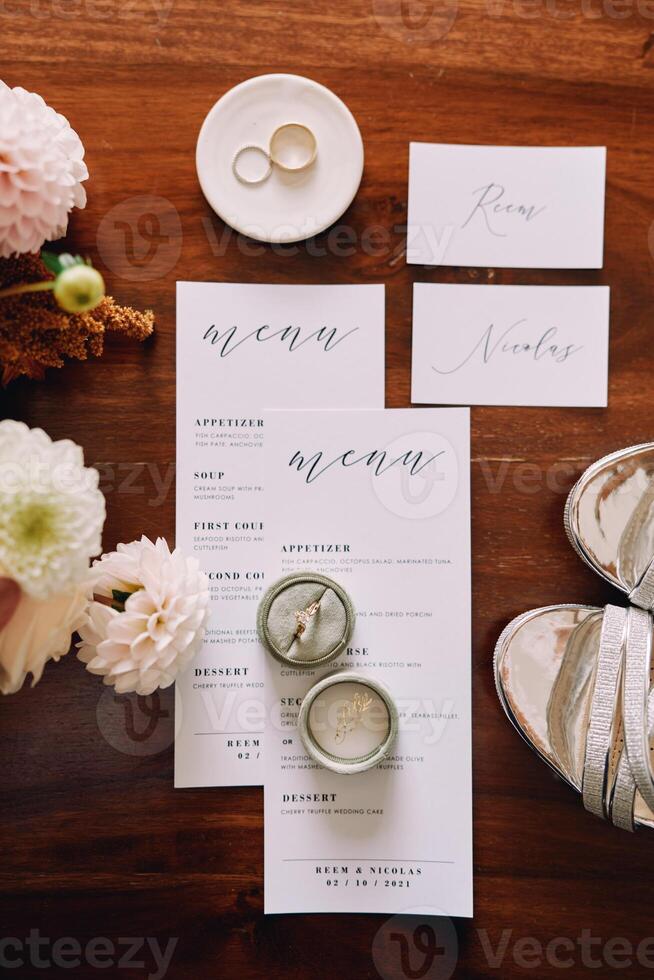 Wedding rings in a box and on a saucer lie on a menu on a wooden table. Top view photo