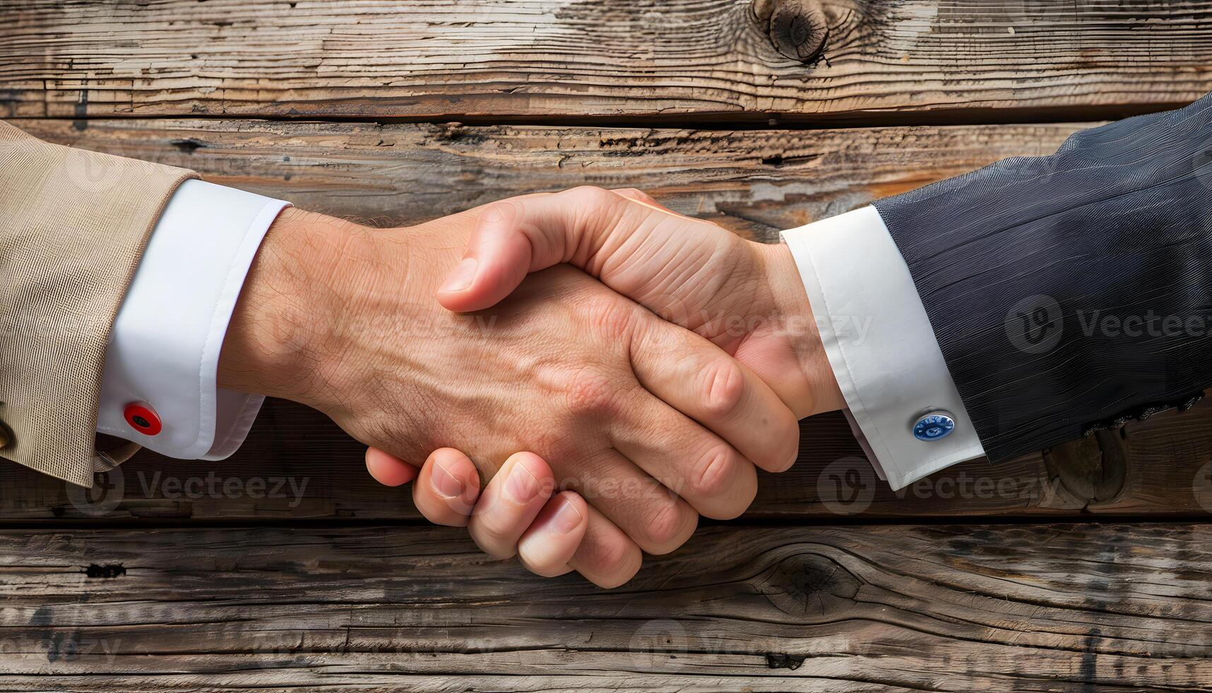 Two men in formal wear are sharing a handshake on a wooden table photo
