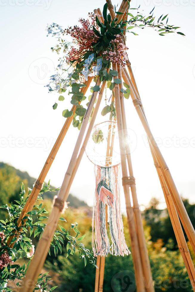 Sun shines through the top of a wedding tipi arch in the mountains photo