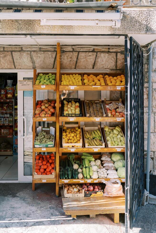 Wooden boxes with fresh vegetables and fruits stand on a store counter on the street photo