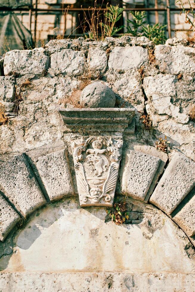 Carved coat of arms on a keystone on an old stone wall photo