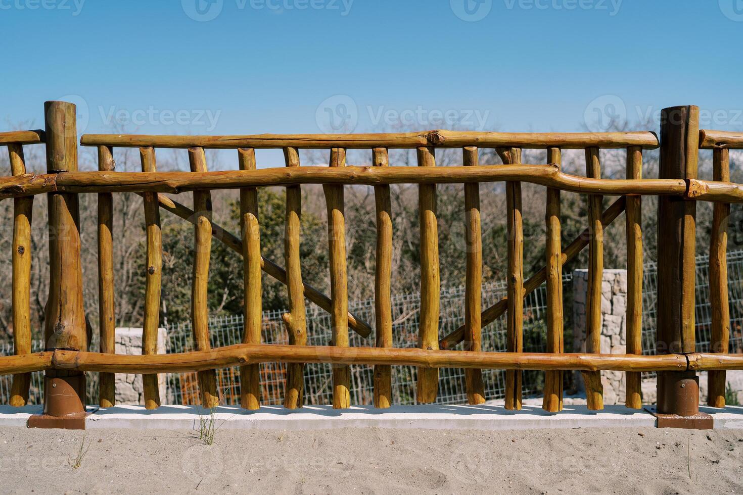 Wooden rustic fence in the park against the background of green trees and blue sky photo