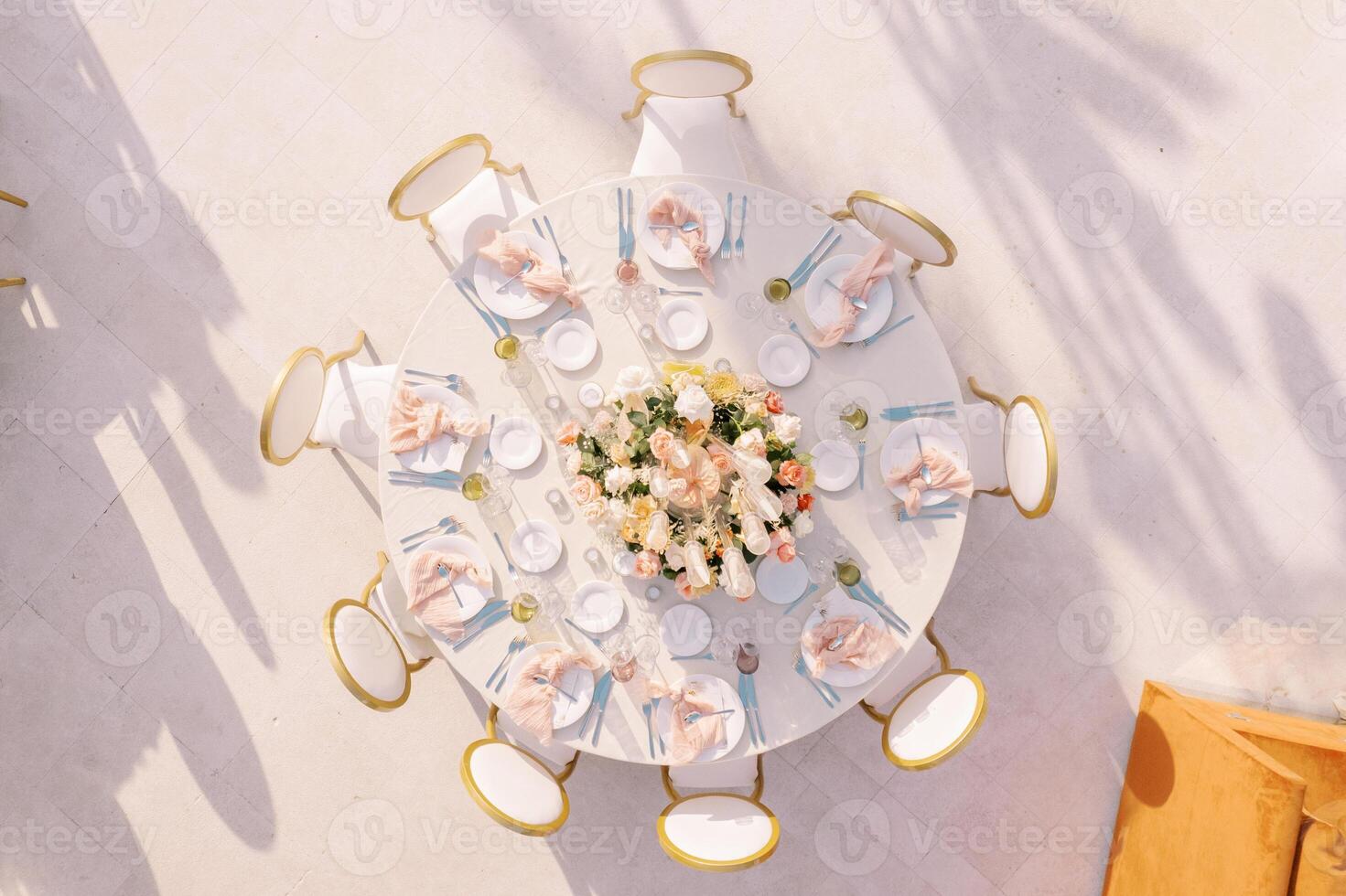 Festive round table with chairs stands in an open area. Top view photo