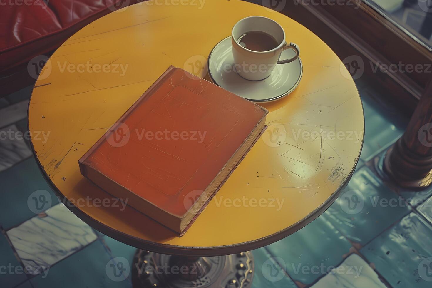 A book, a cup of coffee, and tableware on a yellow wood table photo