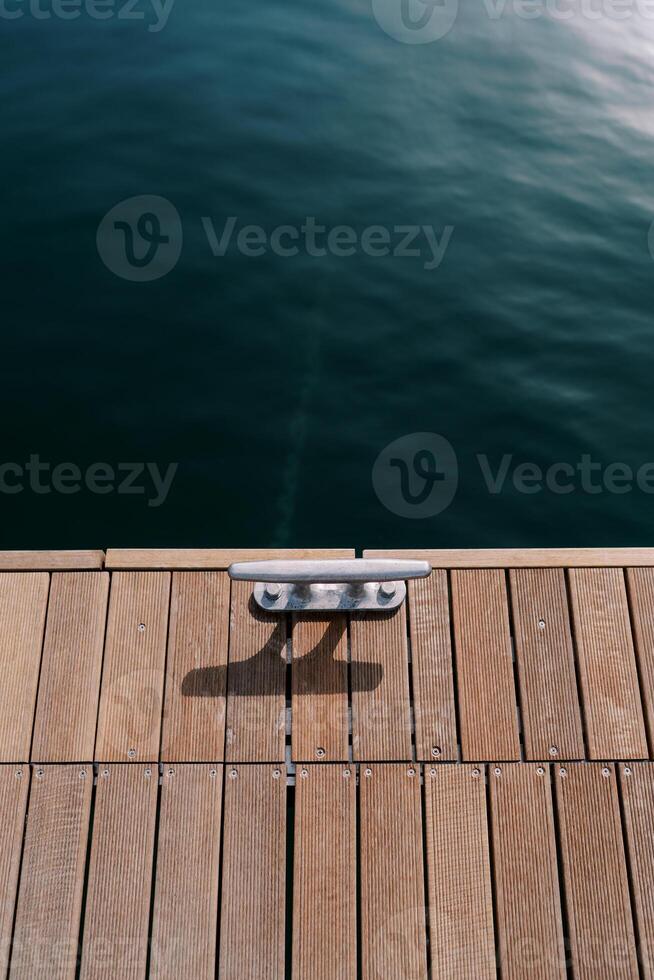 Wooden pier with bollard by the sea. Top view photo