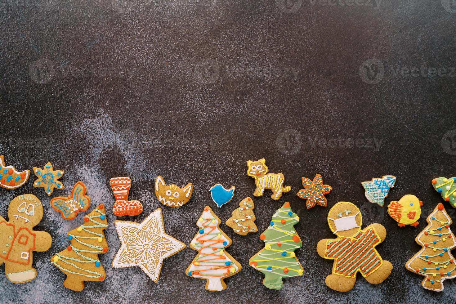 Christmas glazed cookies lie along the bottom edge on a black shabby background photo