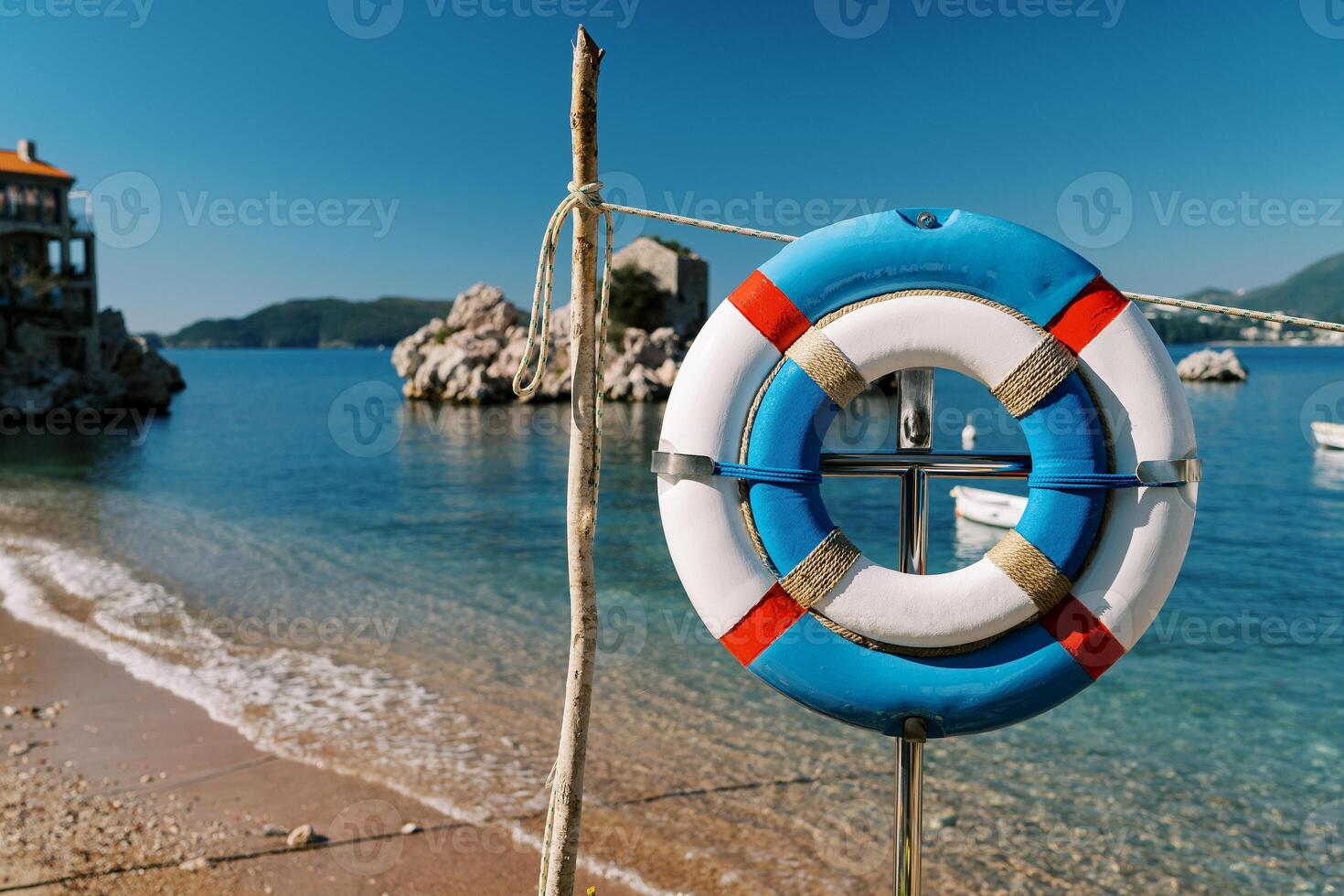Large and small lifebuoys hanging on a rack on a sandy beach photo