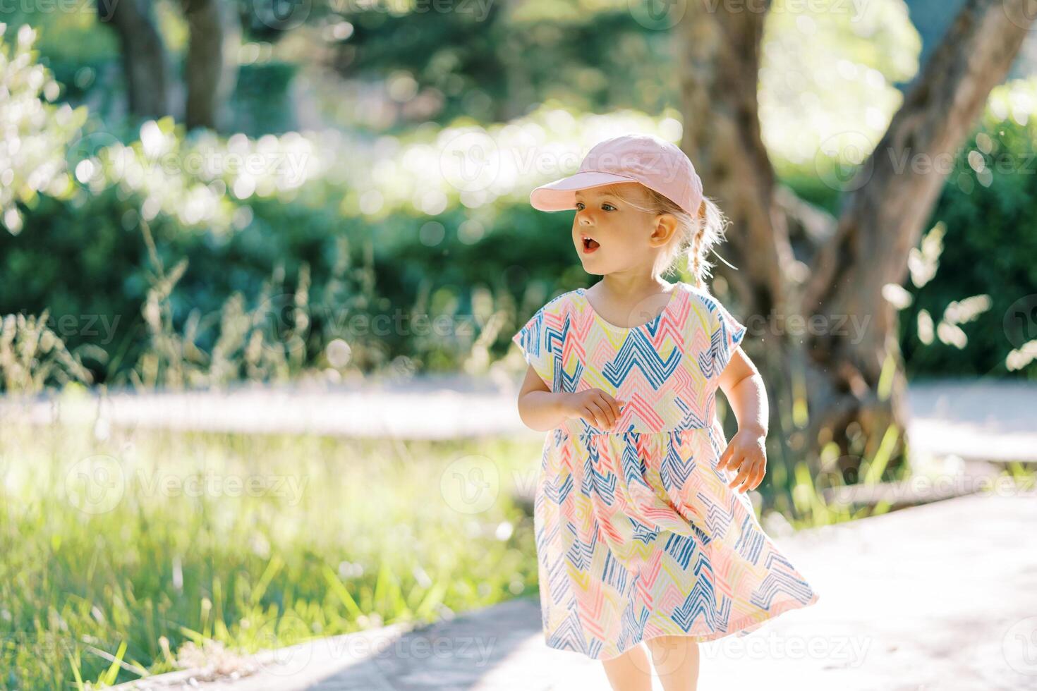 Little girl runs with her mouth open along a path in the park photo