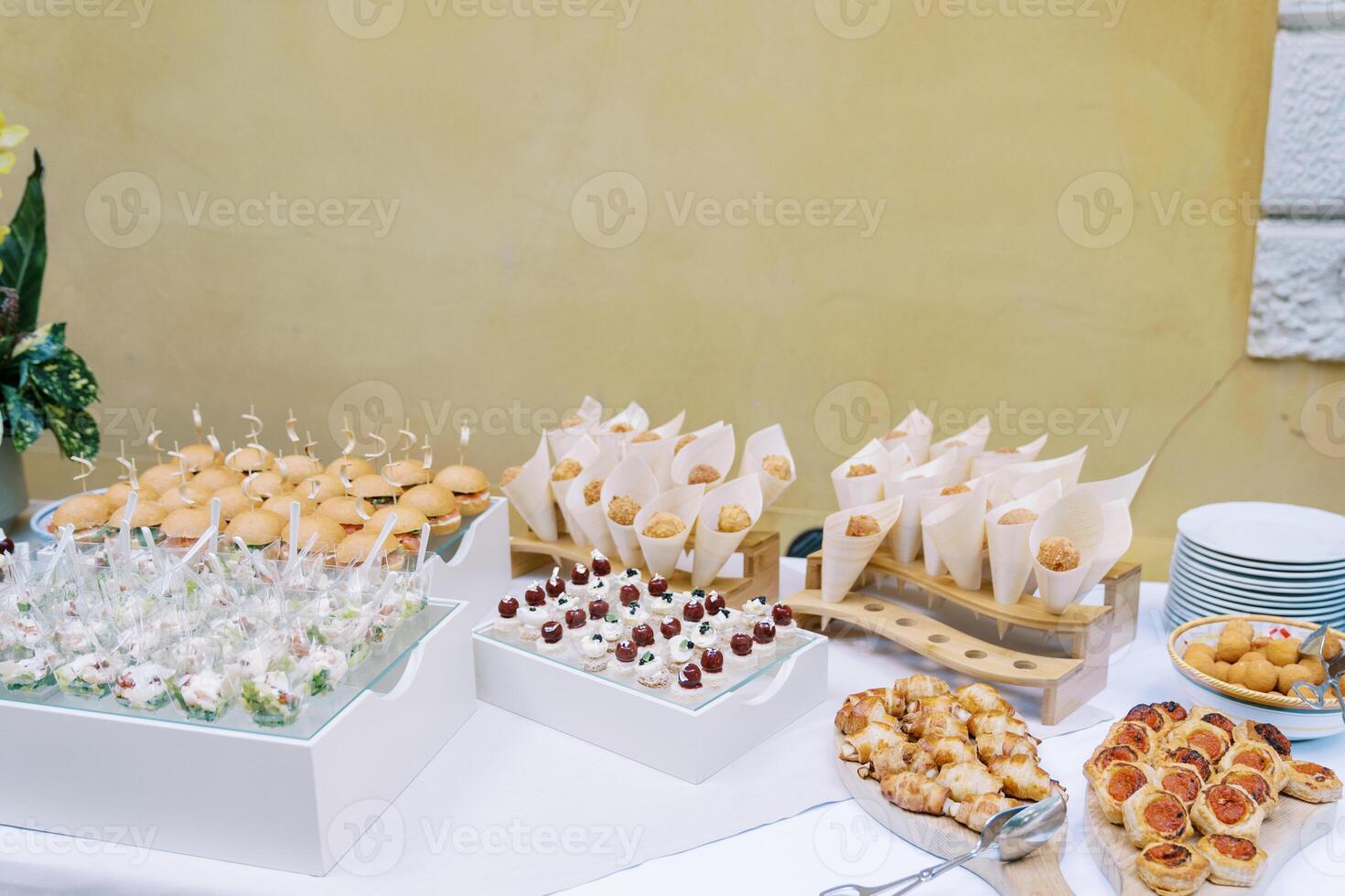 Festive table with appetizers, portioned salads, mini-burgers and cakes photo