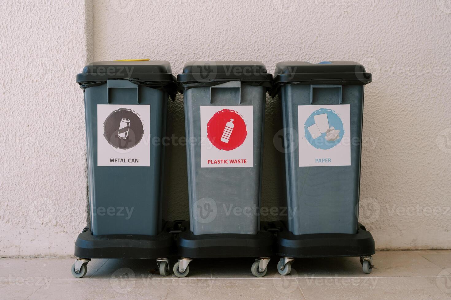 Garbage bins for separate waste are located near the wall of the house. Inscription. metal can, plastic waste, paper photo