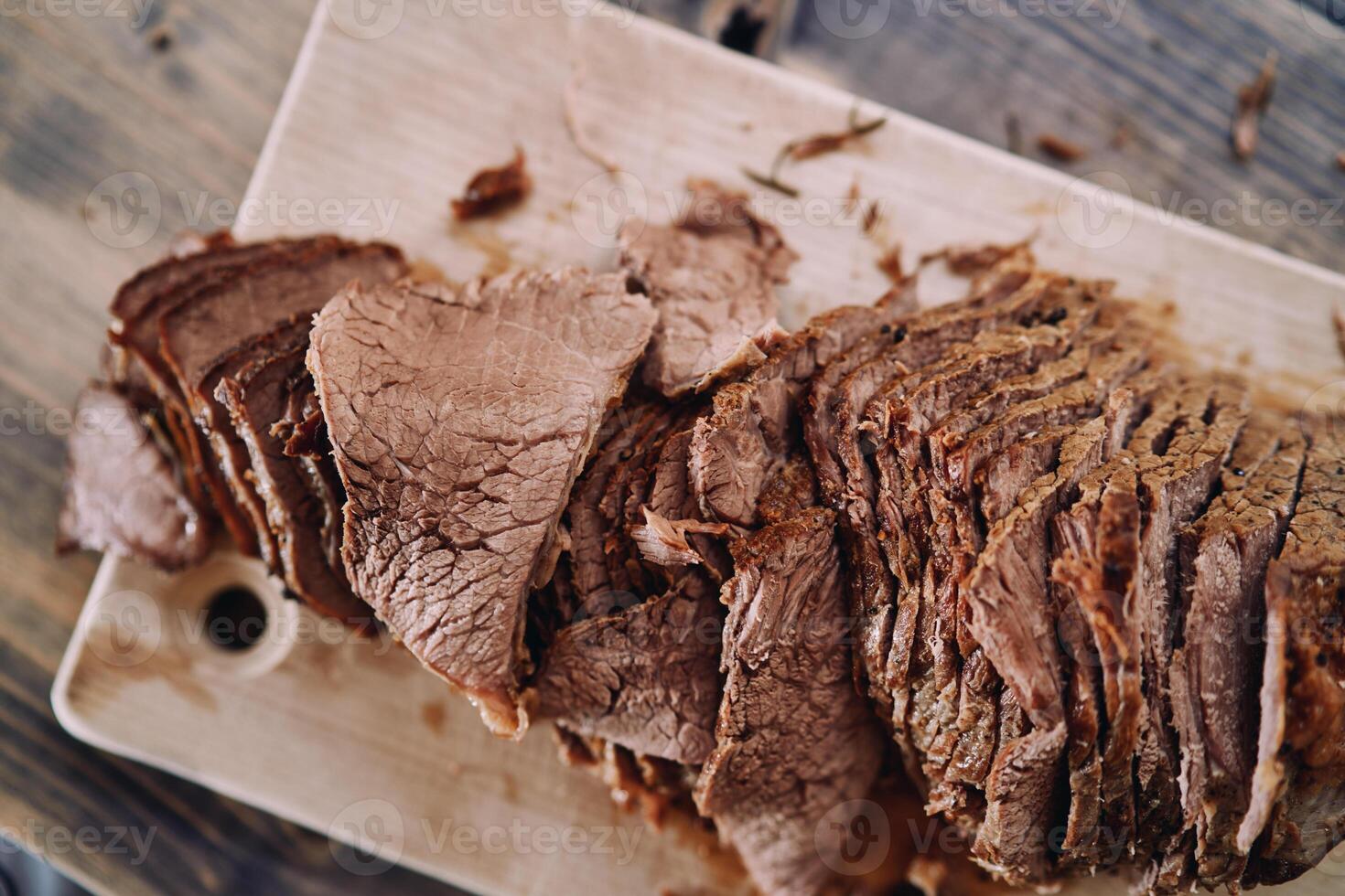 Slices of juicy roast beef lie in a row on a cutting board photo