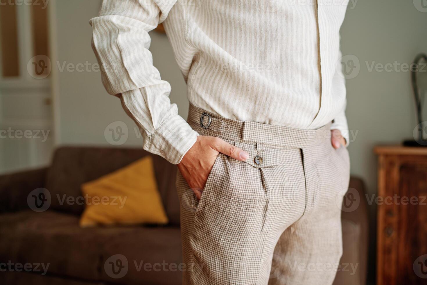 Groom stands in the room with his hands in his trouser pockets. Cropped. Faceless photo