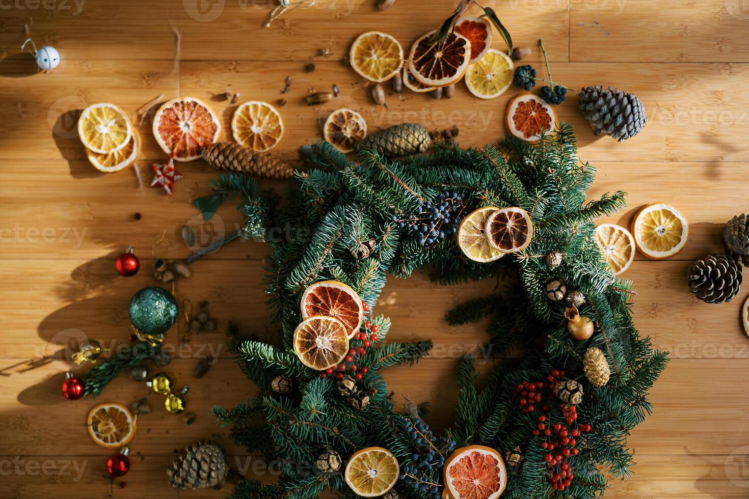 Pieces of dried oranges, toys and fir cones lie near the Christmas wreath on the floor photo