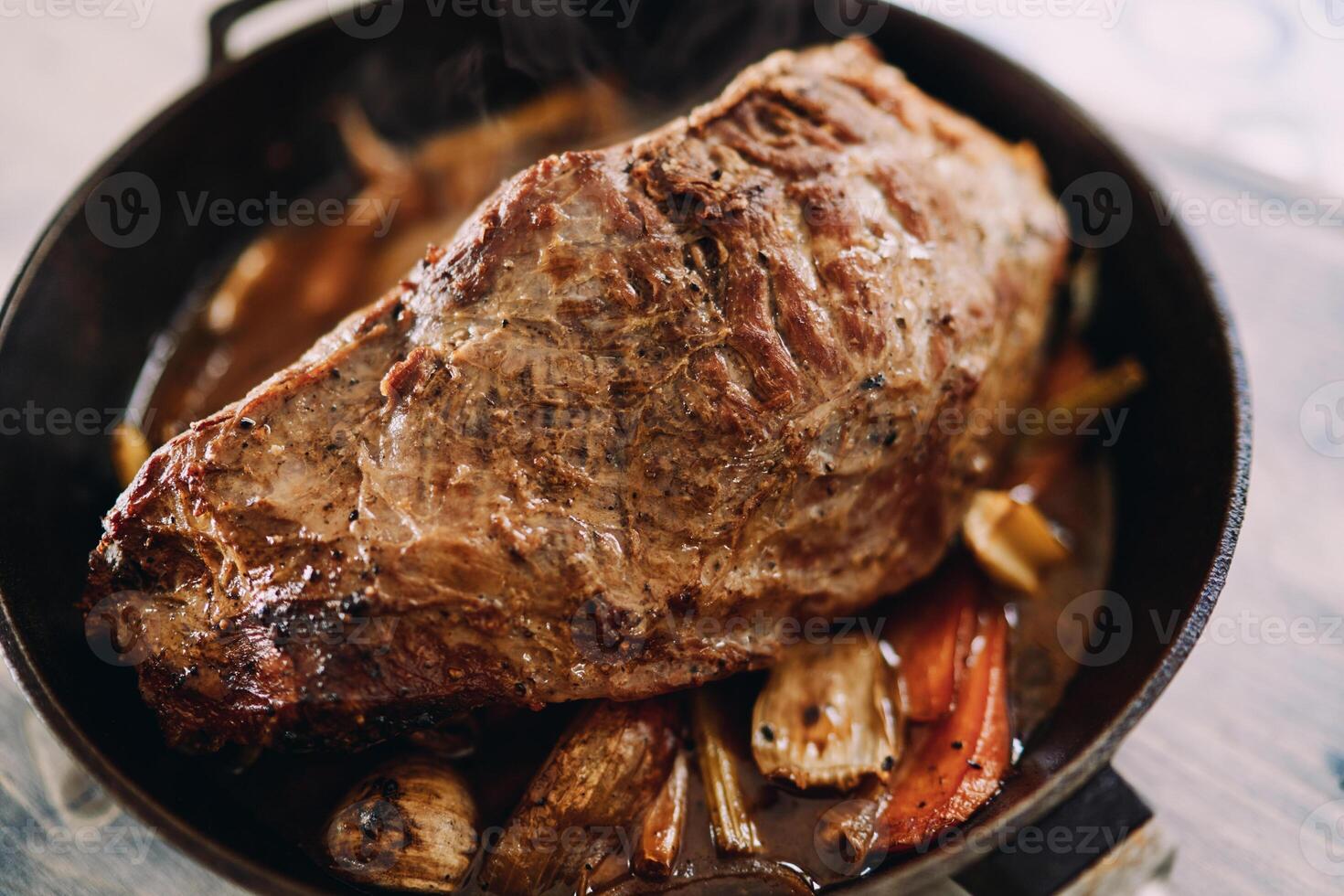 Baked roast beef with vegetables is in a frying pan. Top view photo