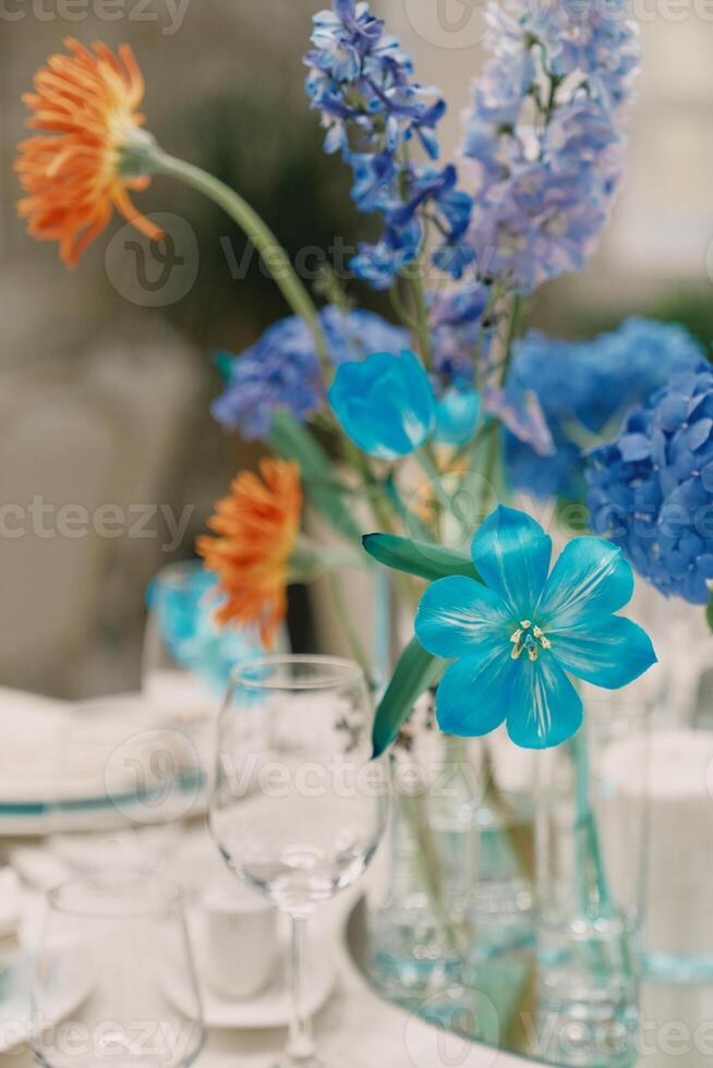 Bouquet of flowers stands on the table near the glasses photo
