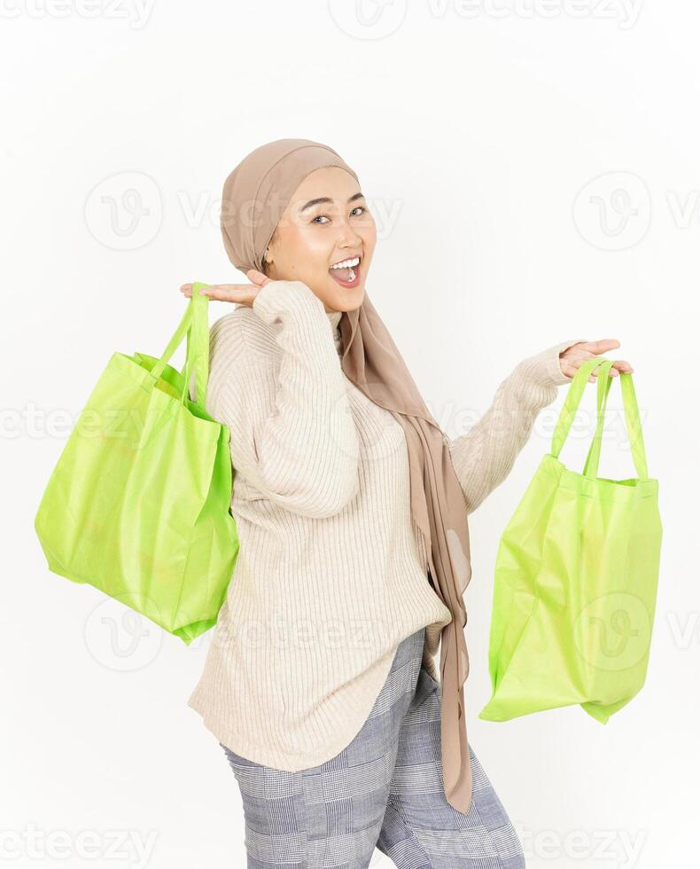 A woman in a hijab holding two green shopping bags photo