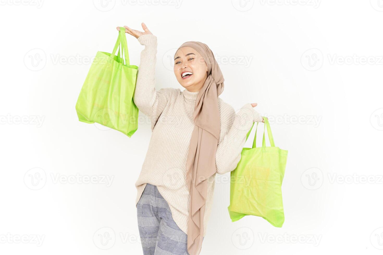A woman in a hijab holding two green shopping bags photo