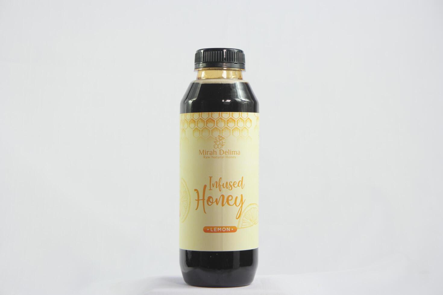 Beautifully designed honey bottle with a rustic label, placed beside a honey dipper and a bowl of fresh fruit photo