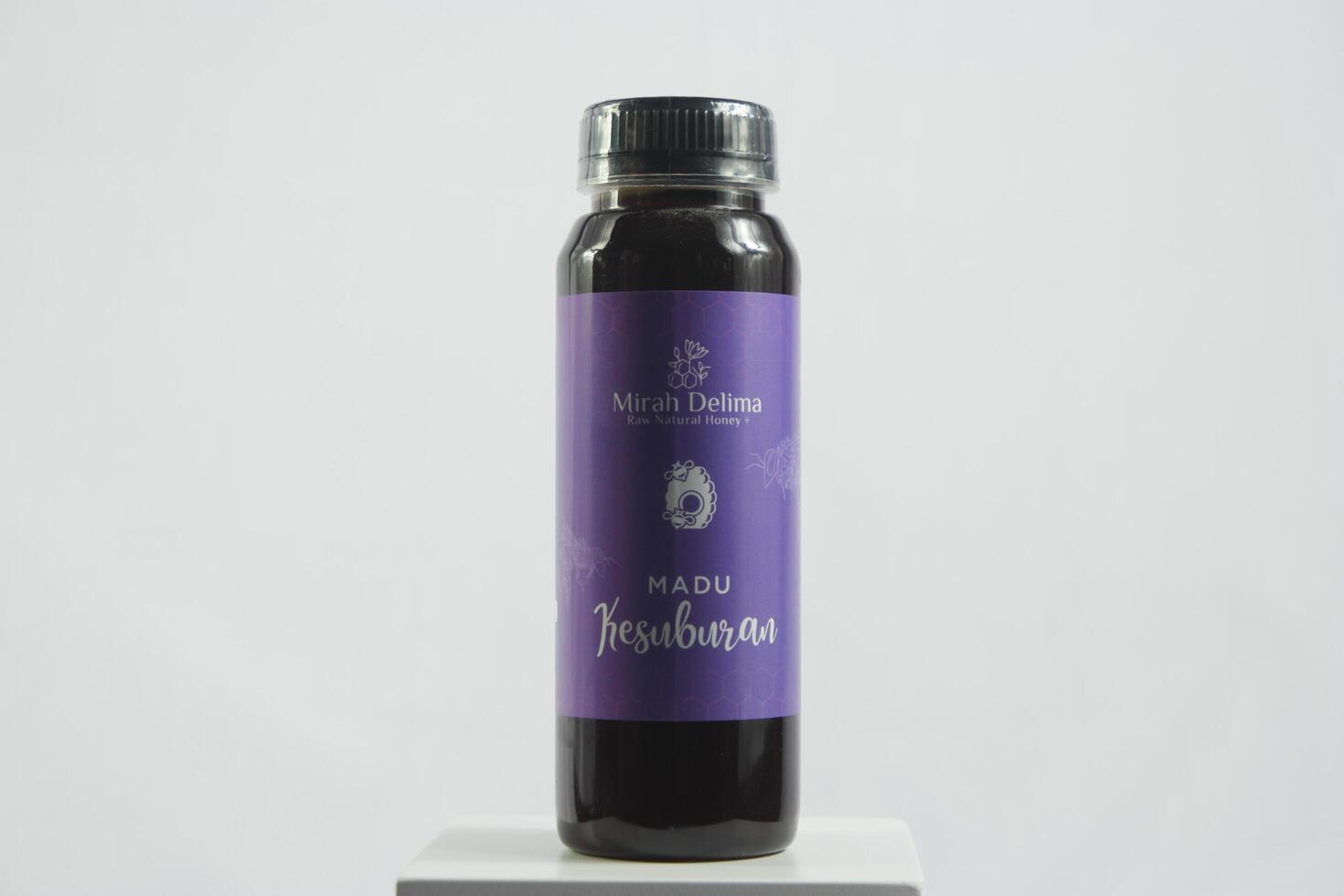 A bottle of purple syrup on a white surface photo