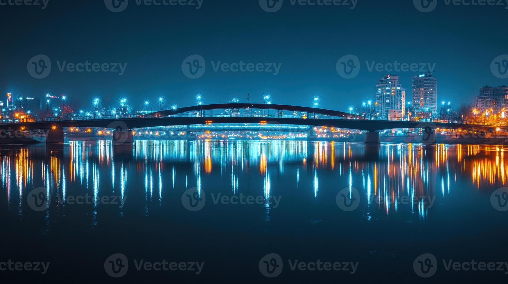 A night view of a bridge illuminated by city lights reflecting on the water. photo