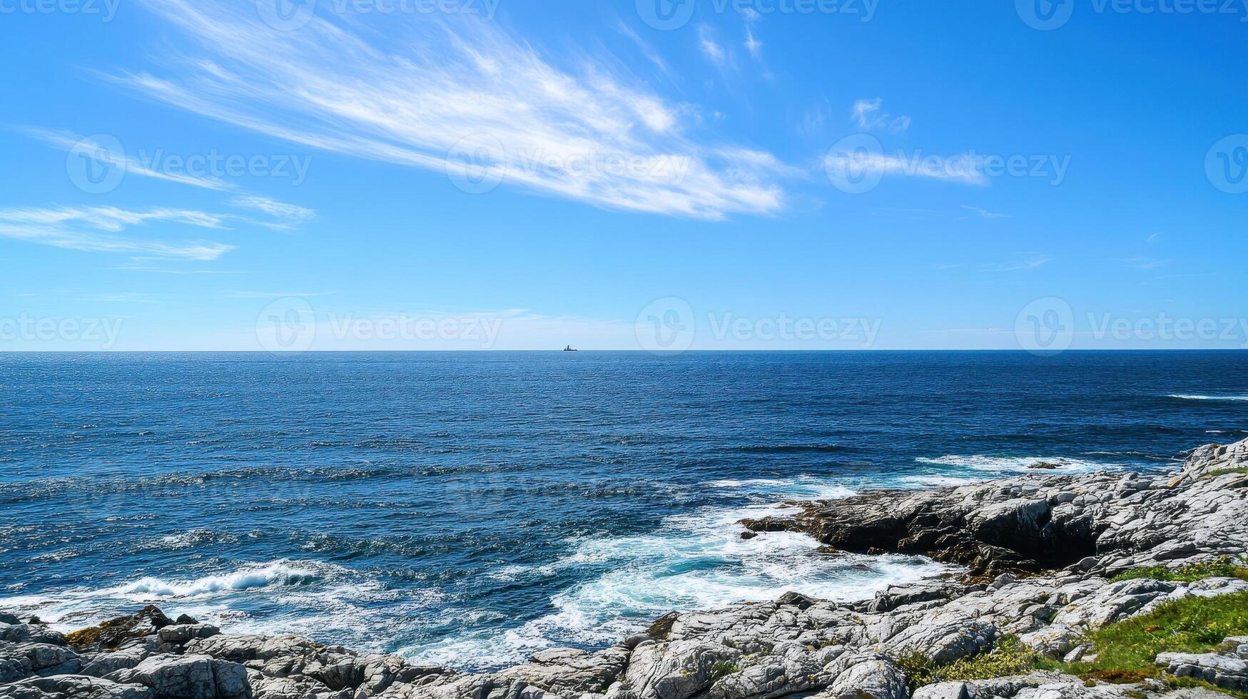 A serene coastal landscape with rocky shores and a clear blue sky over the ocean photo