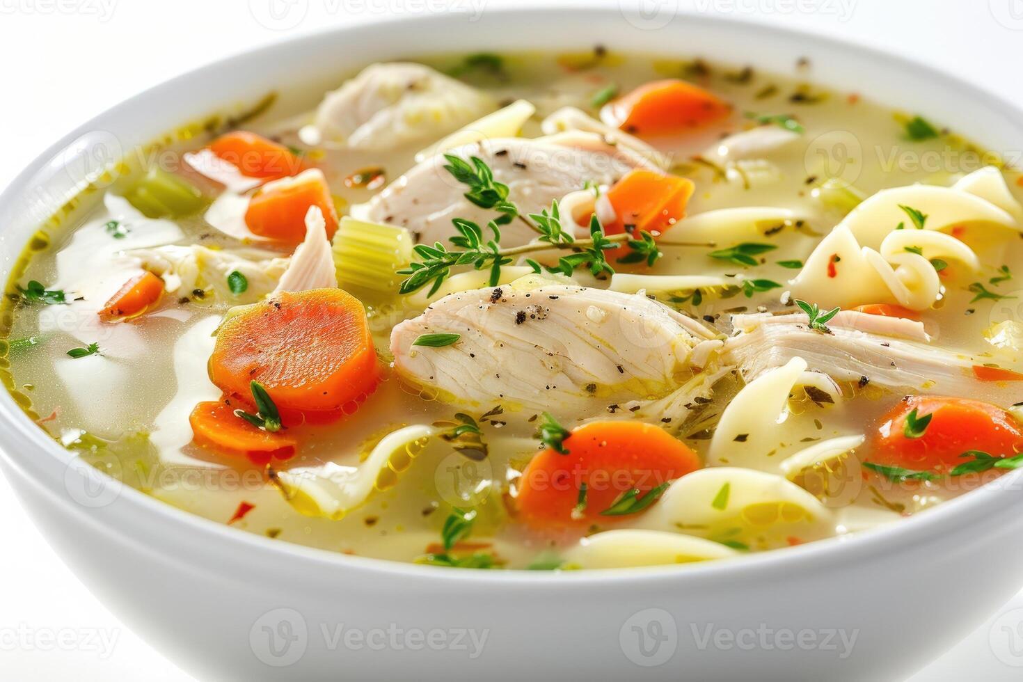 A bowl of chicken noodle soup with vegetables and herbs, showcasing a comforting meal photo