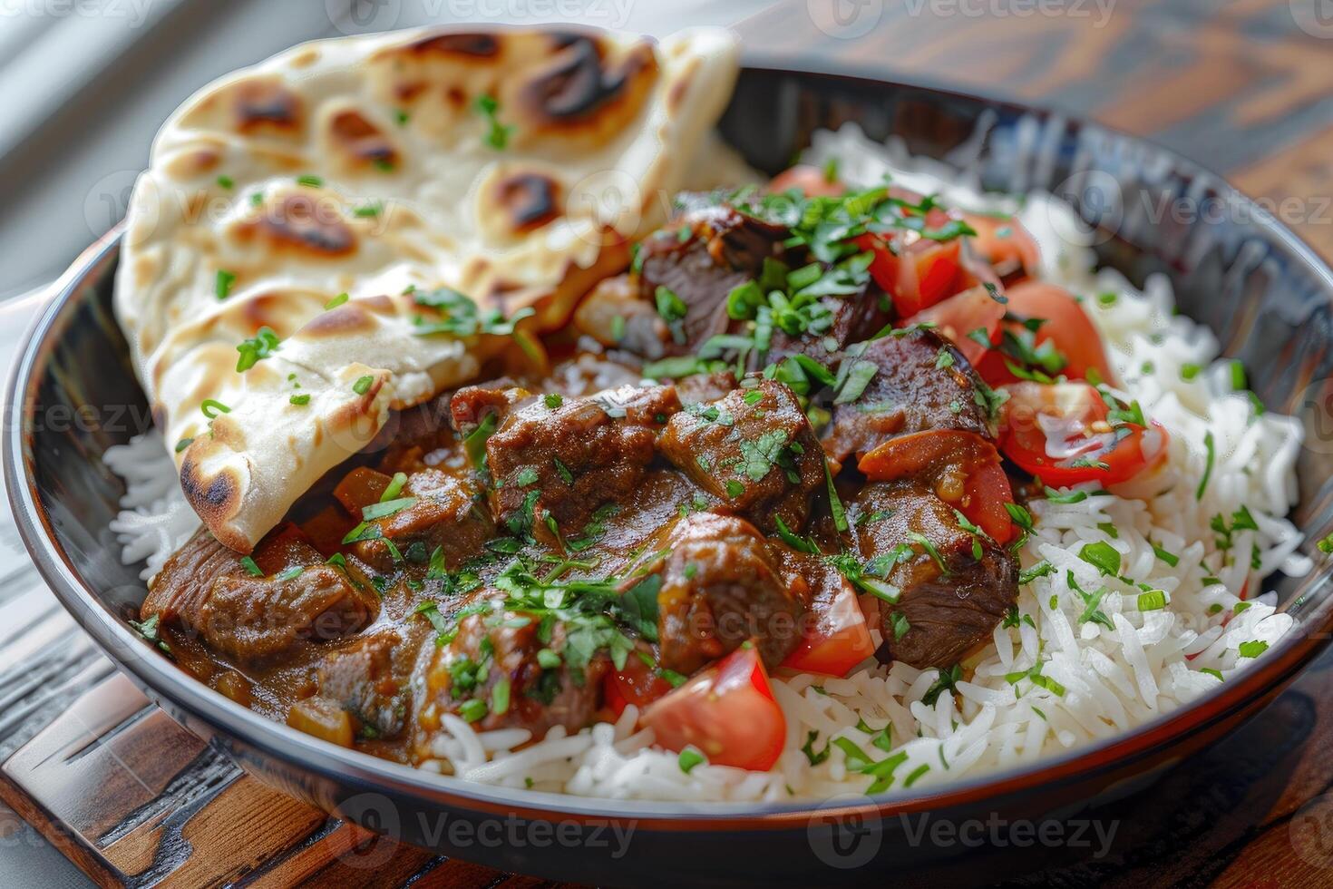 A bowl of rice topped with beef, tomatoes, and herbs, served with naan bread. photo
